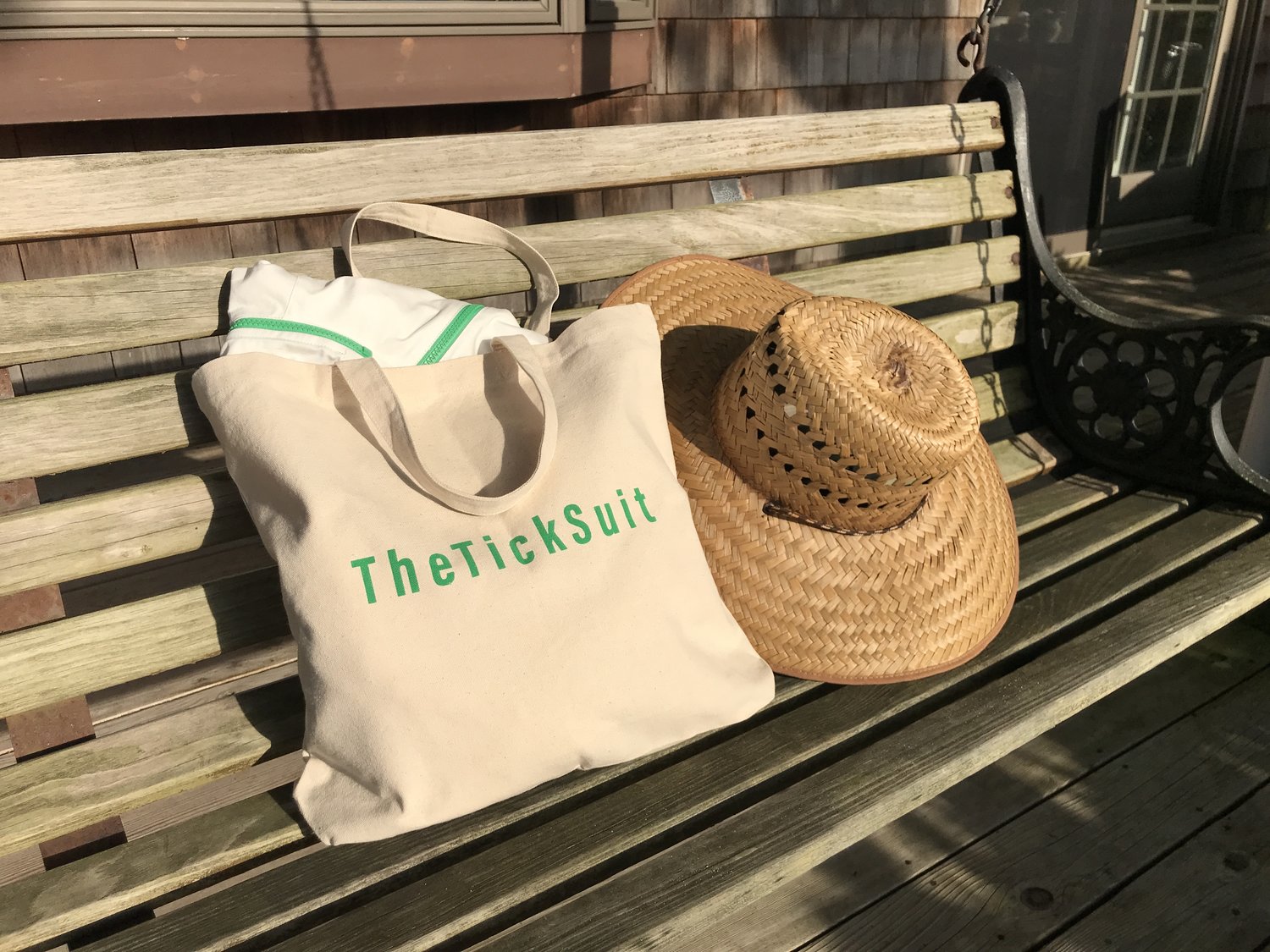 TheTickSuit inside a tote back with "TheTickSuit" logo on a bench next to a straw hat